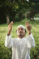 hombre musulmán religioso rezando jamaah en prado verde. foto