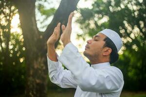 Asian Muslim man praying Allah God Of Islam while raised arms ,Ramadan festival concept photo