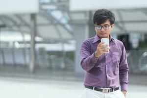 joven empresario asiático mirando mensajes en el celular mientras camina por la calle en el centro de la ciudad moderna foto