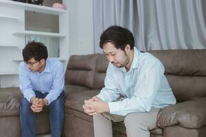 Asian gay couples are quarreling, angry or sad on sofa in home, LGBTQ concept. photo