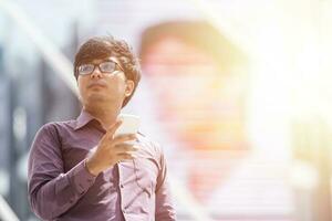 Asian business man purple with tshirtbusinessman looking at messages on cellphone while walking in the street. photo