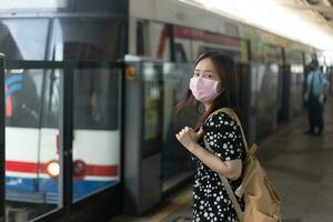Young asian woman passenger waiting to her friend in subway train when traveling in big city photo