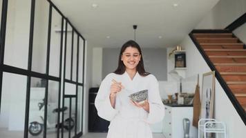 Young woman in robe uses a whisk to mix ingredients in a bowl video