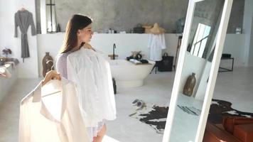 mujer joven en vestido de verano revisa la ropa en el espejo video