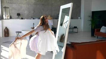 jeune femme en robe d'été vérifie les vêtements dans le miroir video