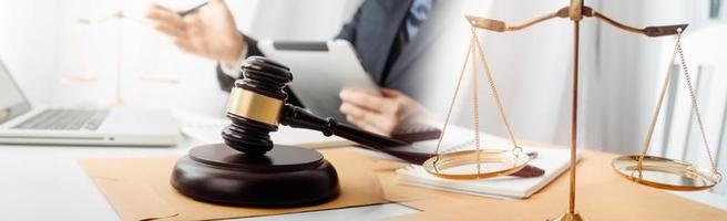 Justice and law concept.Male judge in a courtroom with the gavel, working with, computer and docking keyboard, eyeglasses, on table in morning light photo