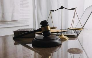 Justice and law concept.Male judge in a courtroom with the gavel, working with, computer and docking keyboard, eyeglasses, on table in morning light photo