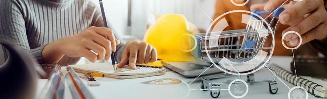 Two colleagues discussing data working and tablet, laptop with on on architectural project at construction site at desk in office photo