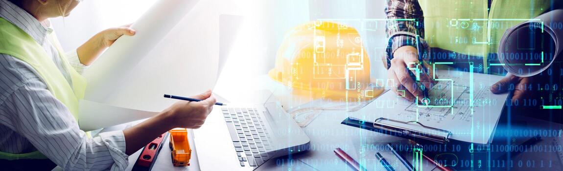 Two colleagues discussing data working and tablet, laptop with on on architectural project at construction site at desk in office photo