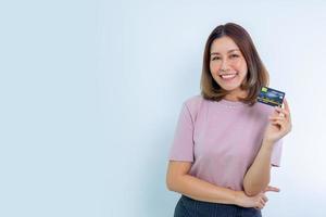 hermosa mujer asiática sonriendo, mostrando, presentando tarjeta de crédito para hacer pagos o pagar negocios en línea foto