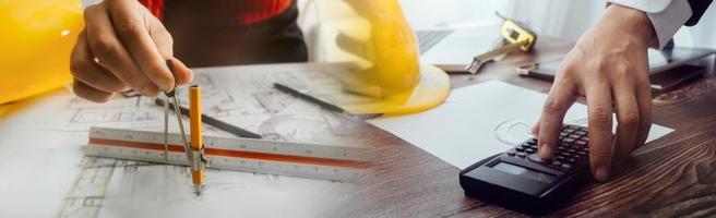 Two colleagues discussing data working and tablet, laptop with on on architectural project at construction site at desk in office photo