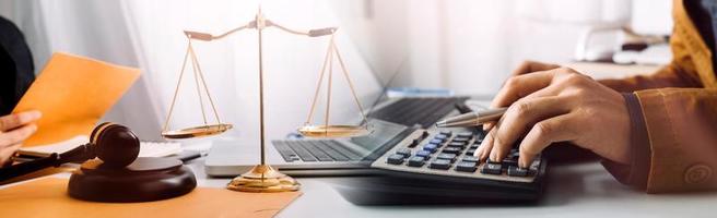 Business and lawyers discussing contract papers with brass scale on desk in office. Law, legal services, advice, justice and law concept picture with film grain effect photo