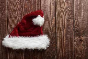 Red Santa Claus hat isolated on wooden background. Space for text. Flat lay. photo