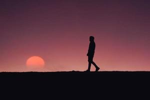 hombre caminando por el campo con un hermoso fondo de puesta de sol foto