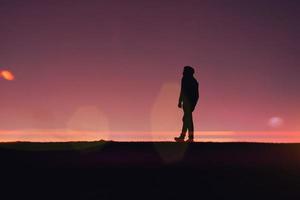 hombre caminando por el campo con un hermoso fondo de puesta de sol foto