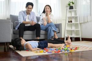 Asian family with children playing and building tower of colorful wooden toy blocks in living room at home, Educational game. photo