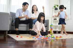 Asian family with children playing and building tower of colorful wooden toy blocks in living room at home, Educational game. photo