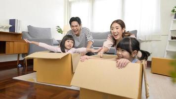 Asian family husband and wife and children with cardboard boxes having fun on moving day, Mortgage, loan, property and insurance concept. photo
