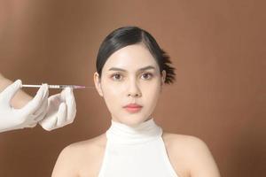 Portrait Beautiful Young Woman face and doctor hands wearing  gloves holding Syringe, Facial Beauty Injections concept photo