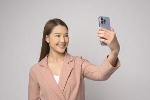 joven asiática usando un teléfono inteligente sobre fondo blanco, concepto de tecnología. foto