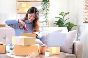 Retrato de mujer joven asiática SM trabajando con una caja en casa el lugar de trabajo.Propietario de una pequeña empresa de inicio, pequeña empresa emprendedora o empresa independiente en línea y concepto de entrega. foto