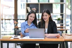 Two Young Asian businesswoman discuss with new startup project Idea presentation, analyze planning and financial statistics and investment market at office. photo