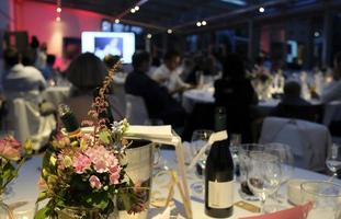 evento nocturno con flores y botellas de vino en las mesas foto