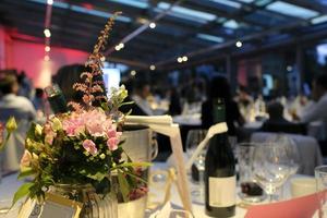 evento nocturno con flores y botellas de vino en las mesas foto