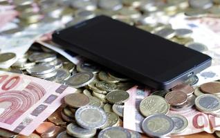 Mobile Payment and Smartphone - a mobile device lying on a pile of money photo