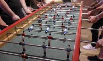 Multiple people playing with an extra-long foosball table or table football photo