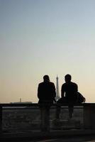 silueta de dos personas disfrutando de una puesta de sol en parís, francia foto