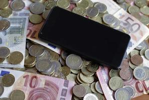 pago móvil y teléfono inteligente: un dispositivo móvil sobre un montón de dinero foto