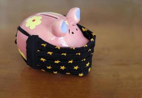 Lockdown and the financial impact - piggy bank wearing a face mask photo