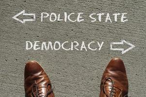 Top view on a man standing in front of the words Police State and Democracy with arrows pointing to the left and right side of the picture photo