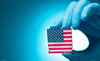 Electronic engineer hand holding computer chip with American flag on blue background. Chipset of electronic circuit board. CPU chip. Computer hardware. Computer processor chip. American computer chip. photo