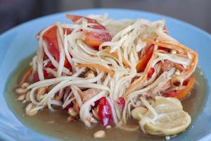 ensalada de papaya de primer plano o los tailandeses llaman som tam thai en placa azul. foto