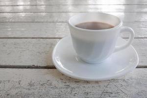 A cup of hot cocoa on white wooden table for the new morning. photo