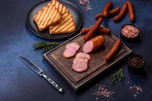 Delicious fresh smoked sausages cut with slices on a wooden cutting board photo