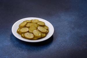 Delicious salted, canned cucumbers cut into slices on a white ceramic plate photo