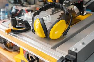 Earmuffs on Electric saw table in workshop .Woodwork safety concept . selective focus photo