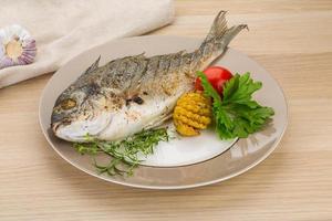 Grilled dorado on the plate and wooden background photo