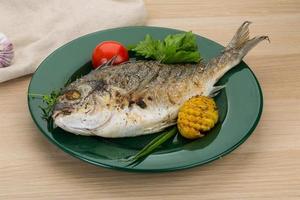 Grilled dorado on the plate and wooden background photo