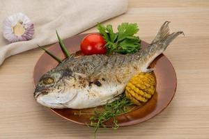 Grilled dorado on the plate and wooden background photo