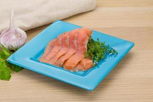 Sliced salmon on the plate and wooden background photo