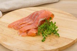 Sliced salmon on wooden board and wooden background photo