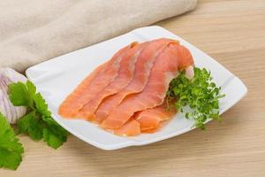 Sliced salmon on the plate and wooden background photo