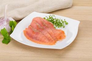 Sliced salmon on the plate and wooden background photo