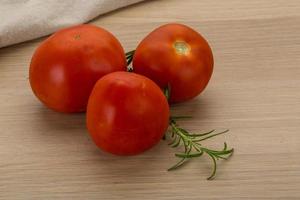 Tomates frescos sobre fondo de madera foto