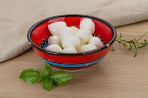 Mozzarella cheese in a bowl on wooden background photo