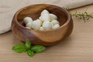 Mozzarella cheese in a bowl on wooden background photo